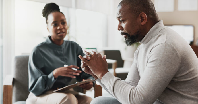 Psychology, therapist and talking in office with patient, discussion and advice for mental health. Black people, therapy and notes in consultation for separation anxiety, mistake or doubt in marriage