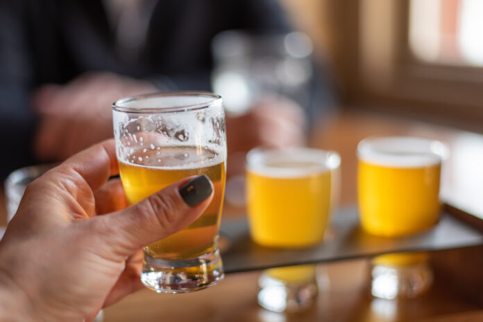 Closeup of a woman holding up a glass of beer while having drinks with friends